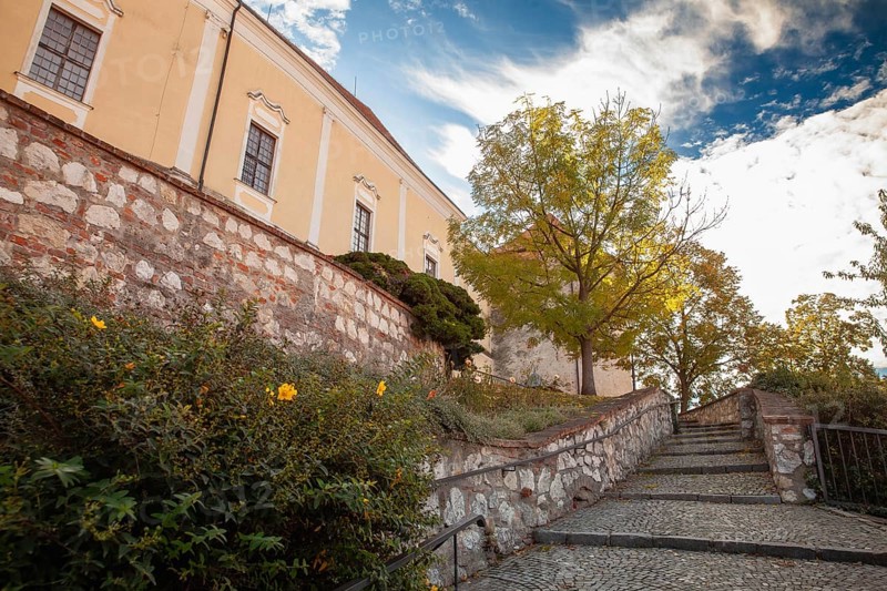 An idyllic path with stone steps and autumn trees leads to a yellow building, Mikulov Nikolsburg Czech Republic