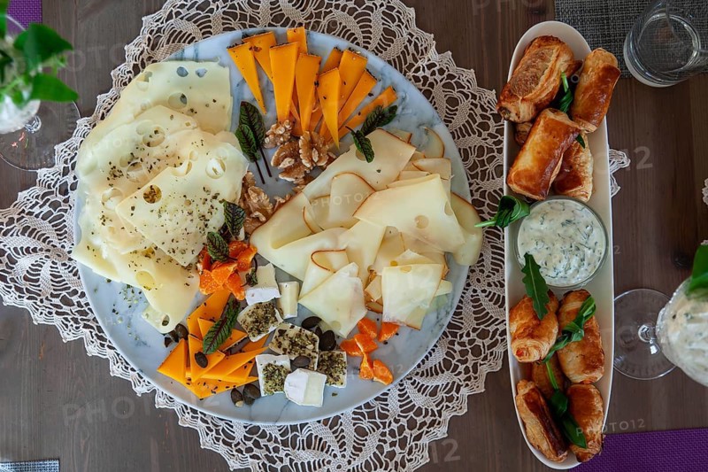 A cheese platter with different types of cheese and dumplings, decorated with herbs on a wooden table, Lower Austria Austria