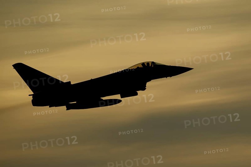 Eurofighter Typhoon silhouette of a military fighter jet aircraft of the Royal air force RAF flying at sunset, England, United Kingdom