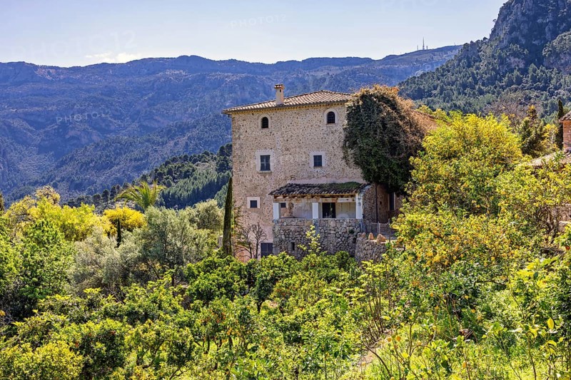 Old stone house in an fruit orchard with lush foliage in a mountainous area, Mallorca, Spain