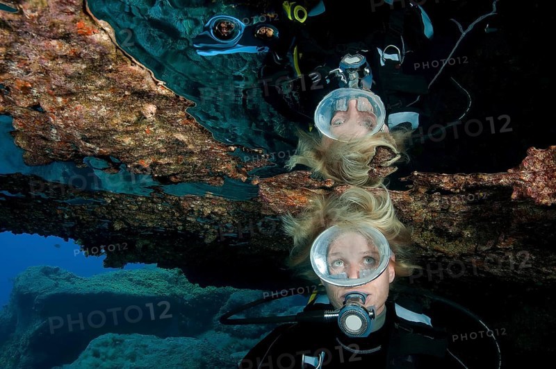 Diver with open blonde hair reflected in large air bubble in cave ceiling in underwater grotto, East Atlantic, Tenerife, Canary Islands, Spain