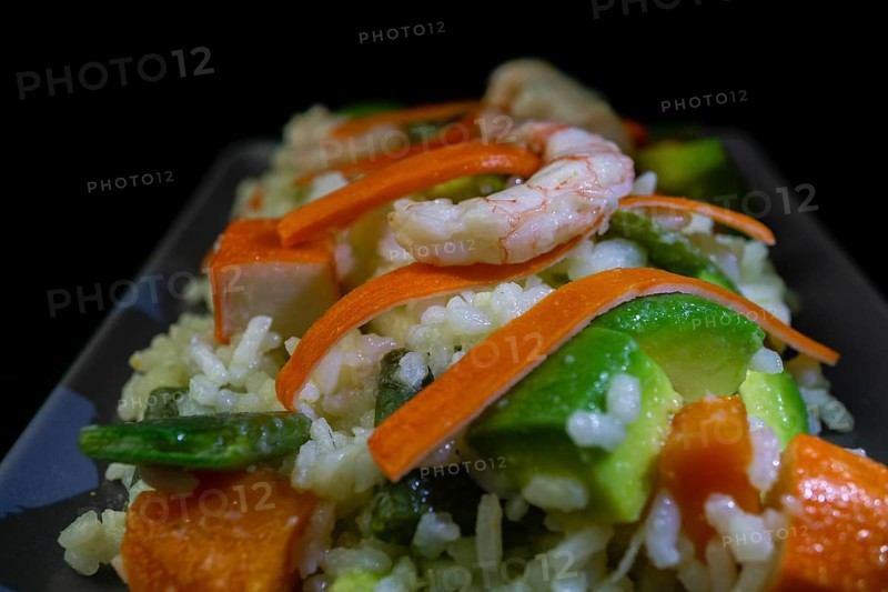 Rice salad with shrimp, red bell pepper and avocado, on black background