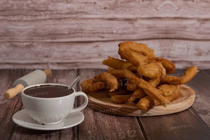 Cup of hot chocolate with freshly made churros on wooden background typical spanish breakfast on holidays