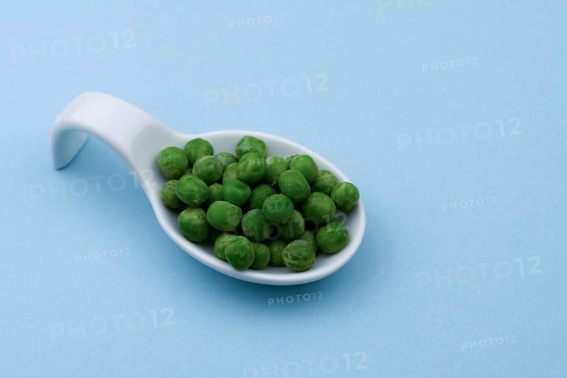 White ceramic spoon with peas and blue bottom