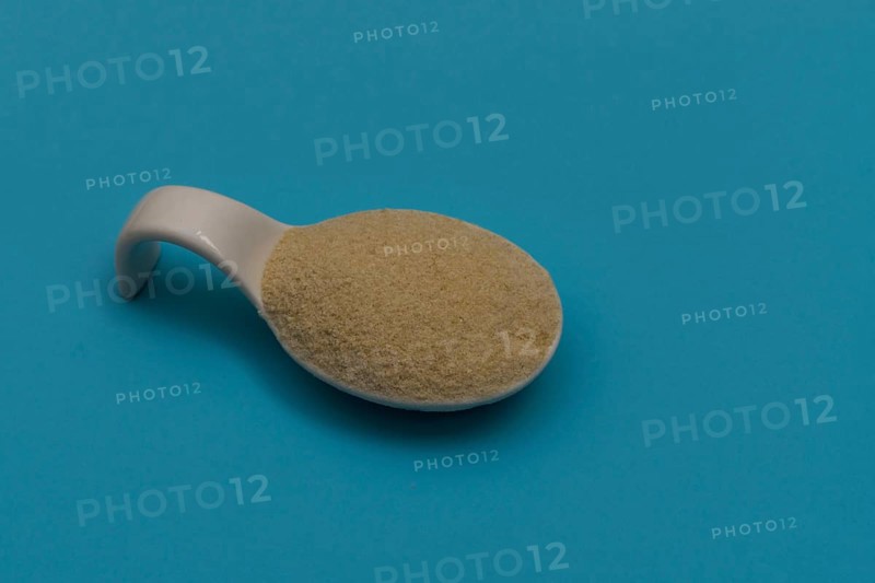 White ceramic spoon with breadcrumbs and blue background