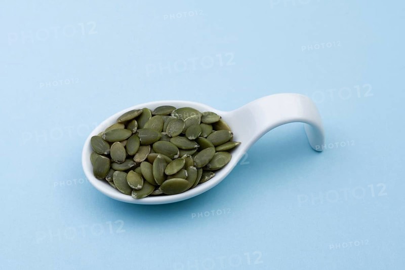 White ceramic spoon with pumpkin seeds and blue bottom
