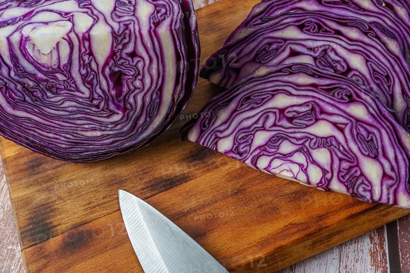 Close-up of a red cabbage or purple cabbage cut with a knife on a wooden board