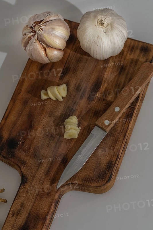 Whole and peeled garlic on wooden board and white background