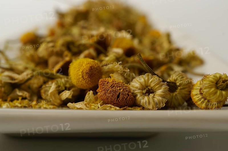 Dried chamomile on a white plate isolated on a white background with copy space