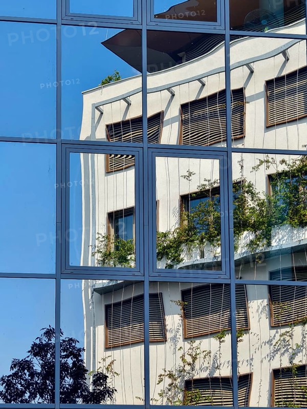 Reflection of a modern building with glass façade and greenery under a blue sky Mödling Lower Austria Austria