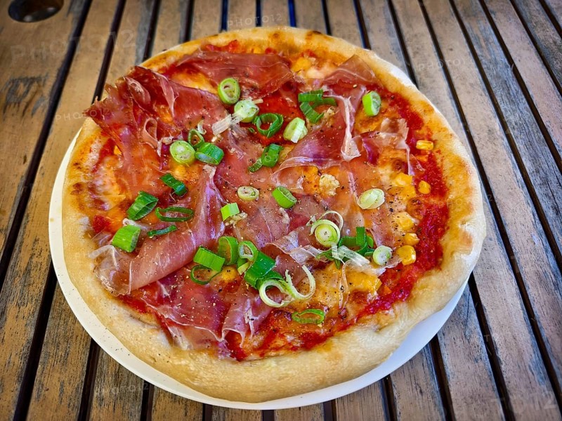 Pizza with ham and spring onions served on a table. Hearty and fresh with an Italian flavour Home-cooked Lower Austria Austria