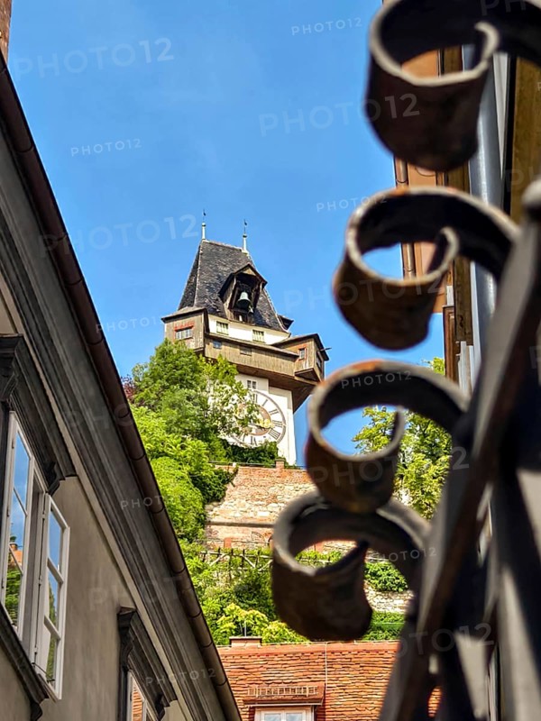 Architecturally richly decorated tower behind a forged fence with a clear sky Graz Clock Tower Graz Styria Austria