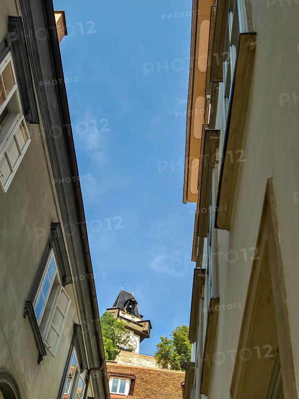 View of a historic tower between old buildings in an old town alley Graz Clock Tower Graz Styria Austria