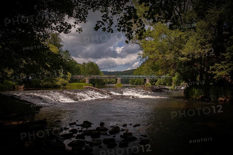 A river with a waterfall and bridge amidst trees and dark clouds Hardegg Weinviertel Lower Austria