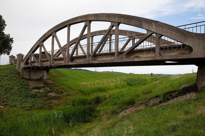 A concrete arch of the bridge stretches across a green meadow under a clear sky Perschling Flood Channel Bridge Lower Austria Austria