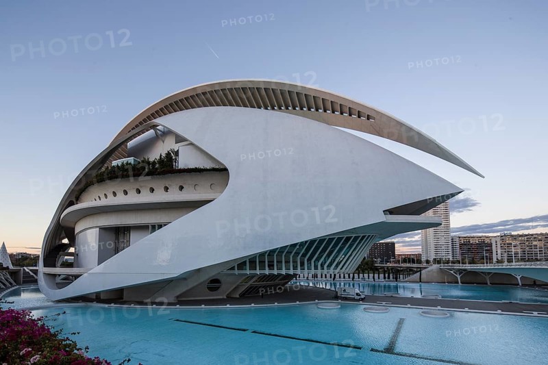 Building with curved white design next to a turquoise-coloured pool under the evening sky Opera