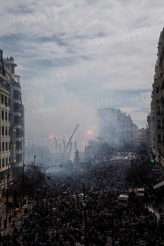 Tightly packed crowd under clouds of smoke on a city street MascletÃ¡ de Fallas