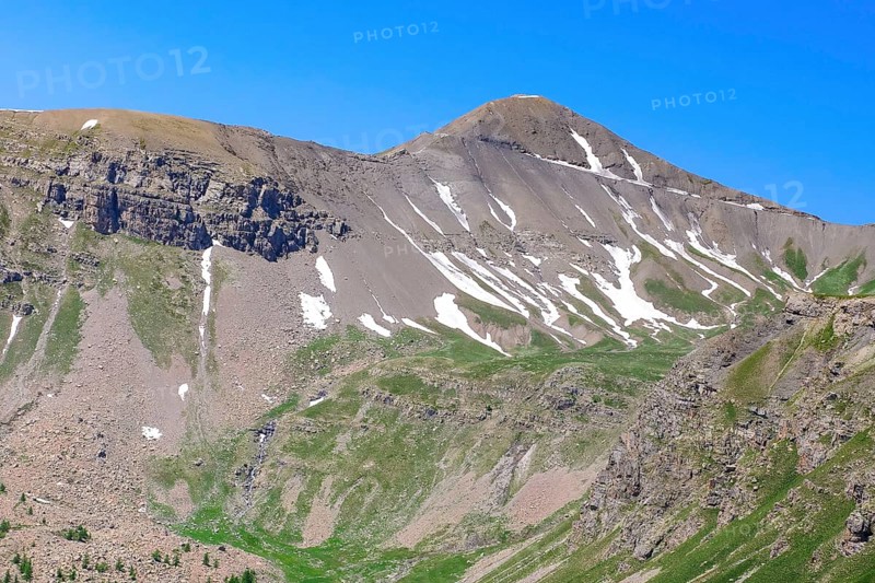 View to the rear eroded steep rocky slope mountainside slope with gravel rock thawing snow remains top right hilltop above 2802 metres high alpine road Cime de la Bonette, Mercantour National Park, Jausiers, Departement Alpes-de-Haute-Provence, France