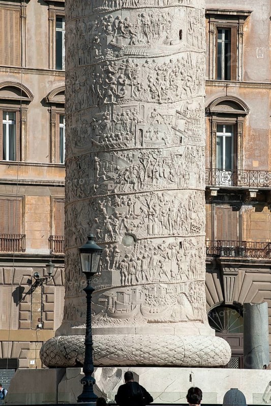 View of part of pedestal and details of spiral marble relief on column of honour Victory Column from year 113 with scenes from wars against the Dacians in Lunensian marble Carrara marble of for Roman Emperor Trajan from antiquity in Trajan's Forum in ancient Rome, Rome, Lazio, Italy