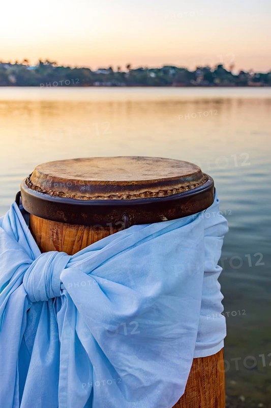 Decorated atabaque in front of the water during sunset, Pampulha lagoon, Belo Horizonte, Minas Gerais, Brazil