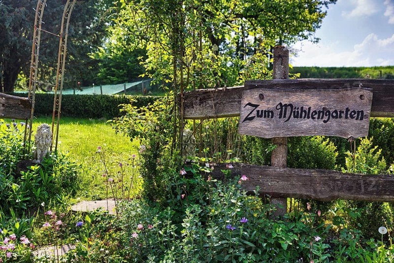 Wooden sign on the garden fence in summer, inscription, Zum MÃ¼hlengarten, country inn, historic watermill, LÃ¼gde, Weserbergland, North Rhine-Westphalia, Germany