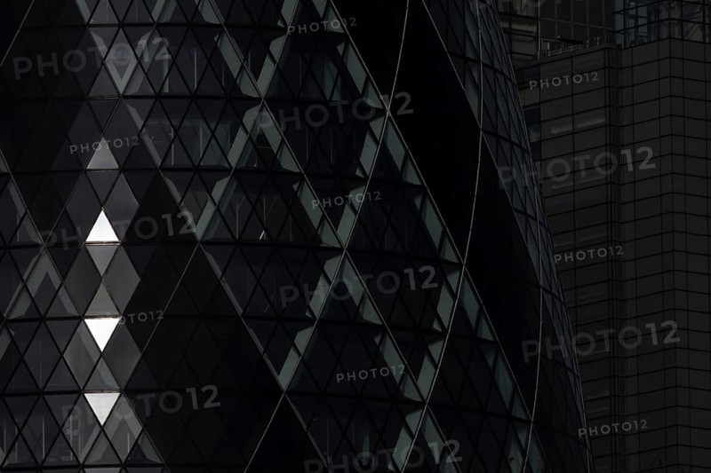 The Gherkin skyscraper building close up of window details with sunlight illuminating three triangle windows, City of London, England, United Kingdom