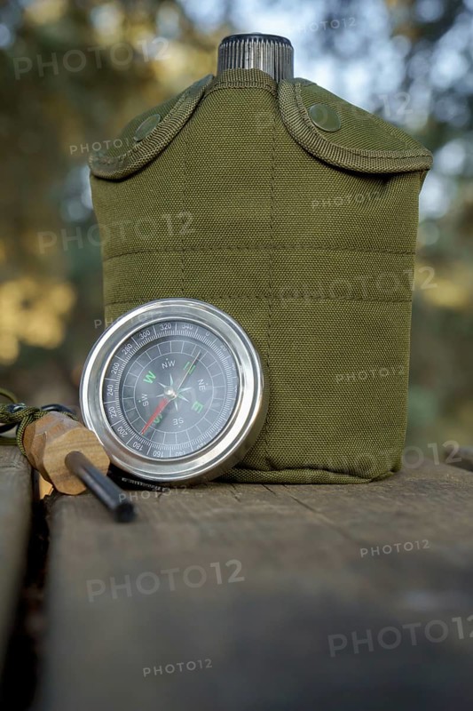Survival kit essentials including compass, canteen, and firesteel are ready for outdoor adventure