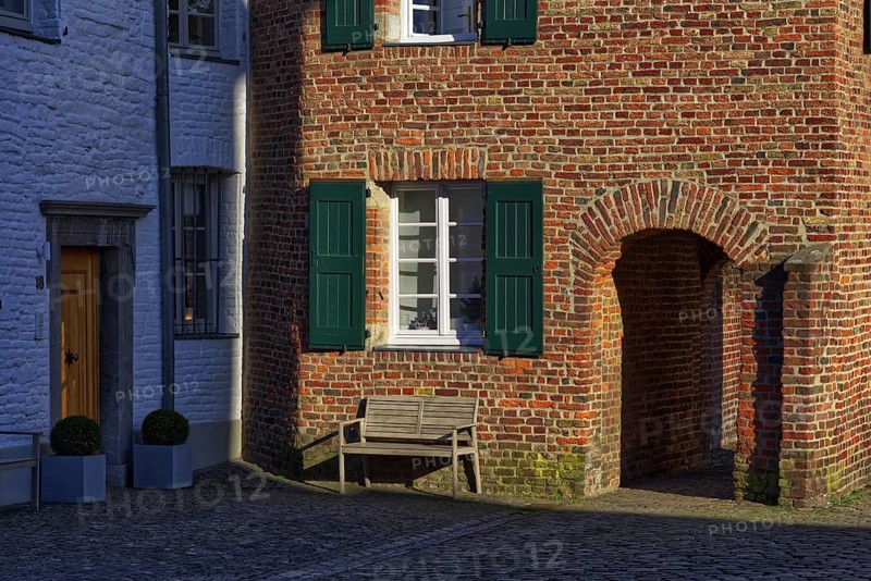 Red brick house with green shutters and bench in the shade, DÃ¼sseldorf