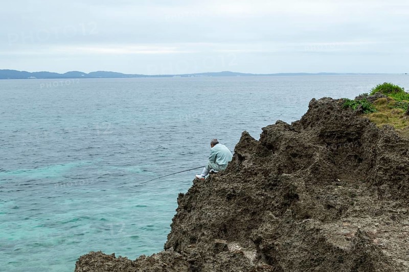 Angler at Sesoko's tail, rock formation, rugged cliffs of volcanic rock at the southern tip of Sesoko-jima, Sesoko Island, Motobu, Kunigami District, Okinawa, Japan