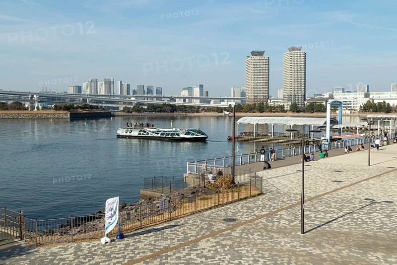 Strollers on the promenade and futuristic Tokyo Cruise Water Bus Queen Emeraldas, excursion boat for harbour cruises in Tokyo Bay, Odaiba, Minato City, Tokyo, Japan
