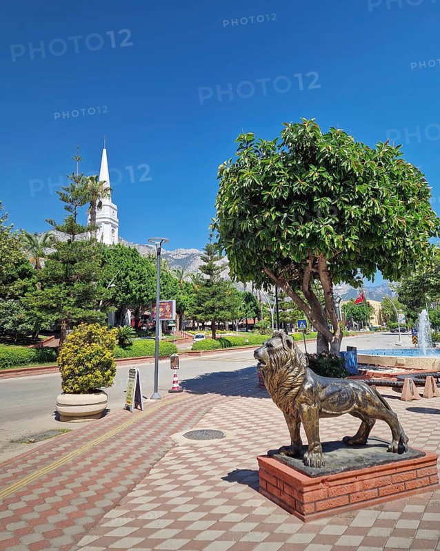 KEMER, TURKEY - JULY 5, 2025 Kemer Saat Kulesi today Cafe Mokka in the city centrum, with view from Ataturk boulevard. Beautiful Taurus mountains in the background