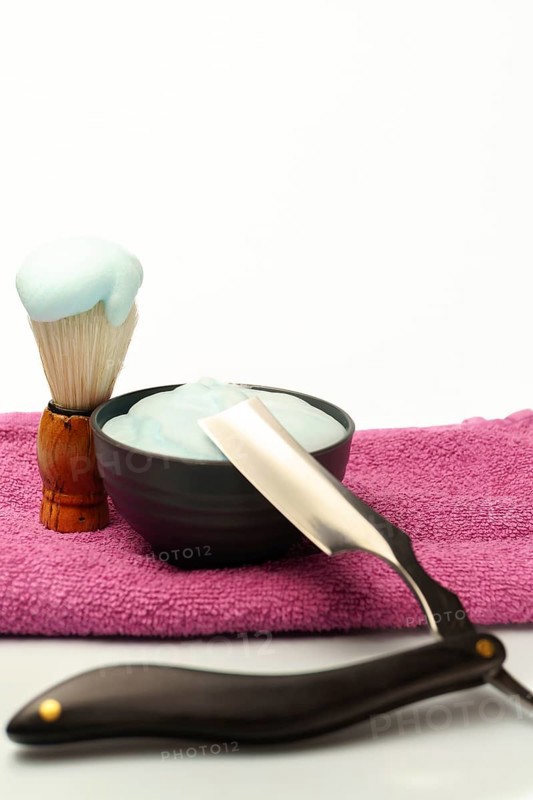 Shaving brush with foam, cream and straight razor are ready for a traditional wet shave