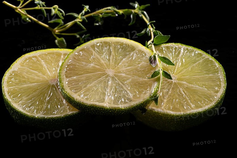 Three lime slices with green decoration on a stone plate