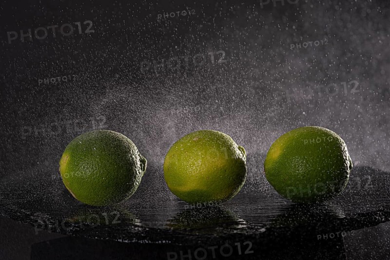 Three limes on a stone slab with drops of water