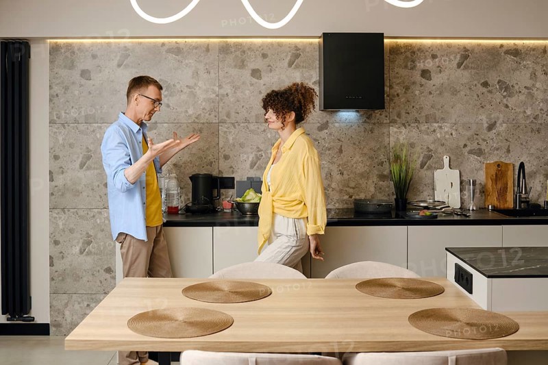 The husband explains his ideas to the young wife actively gesturing his hands during a conversation in the kitchen