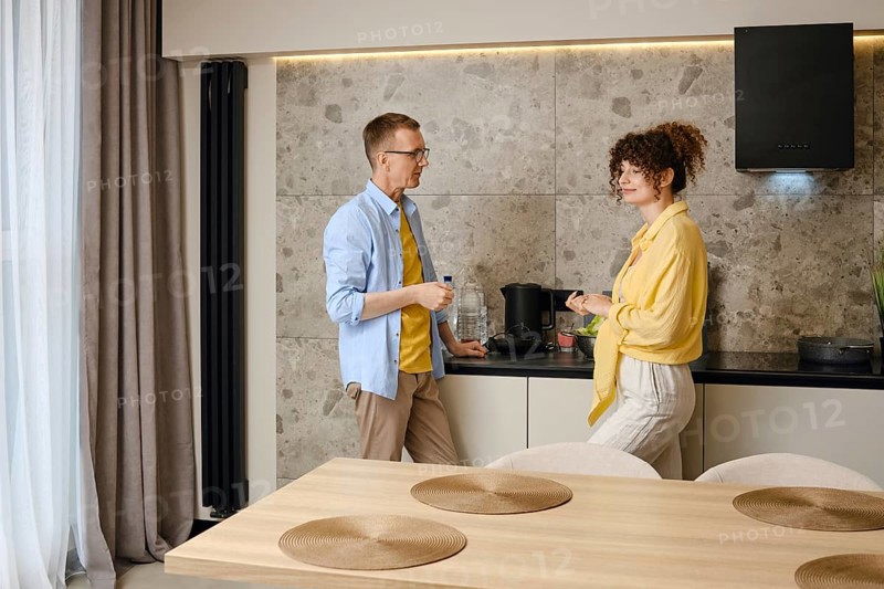 Married couple discusses plans for the near future standing in the kitchen in the morning