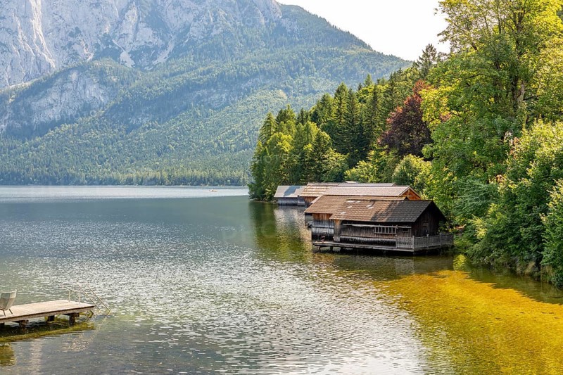 Lake Altaussee with boathouses on the shore, surrounded by wooded mountains, Altaussee, Styria, Austria