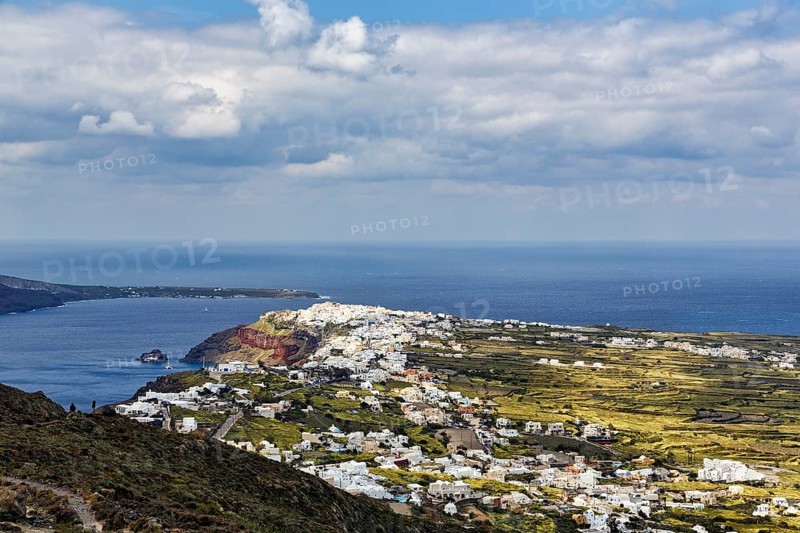Coastline with view of the village of Oia, hiker on hiking trail from Fira to Oia, Thira, Santorini, Cyclades, Greece