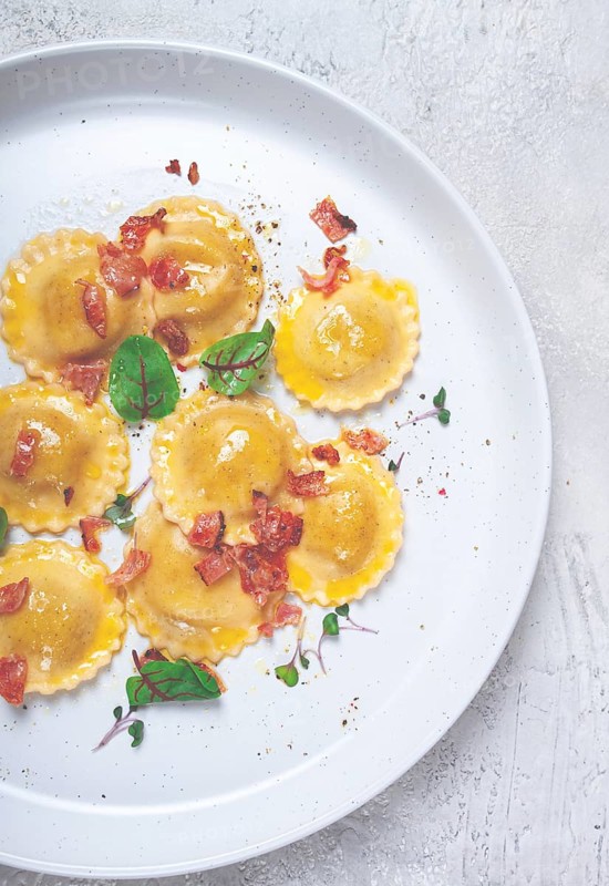Fresh ravioli, with butter, spices and herbs, fried bacon, on the table, top view, light background, no people