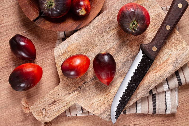 Sliced tomatoes, Black Beauty variety, on a cutting board, top view, on the kitchen table