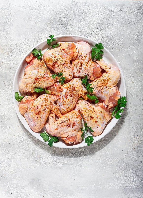 Marinated chicken wings prepared for grilling with spices and fresh herbs ready for cooking