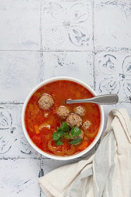 Romanian soup with meatballs, vegetable soup with meatballs, tiled table, homemade, no people