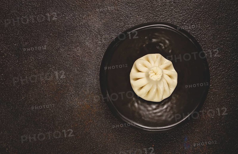 One khinkali, on a black plate, top view, cooking concept, Georgian cuisine
