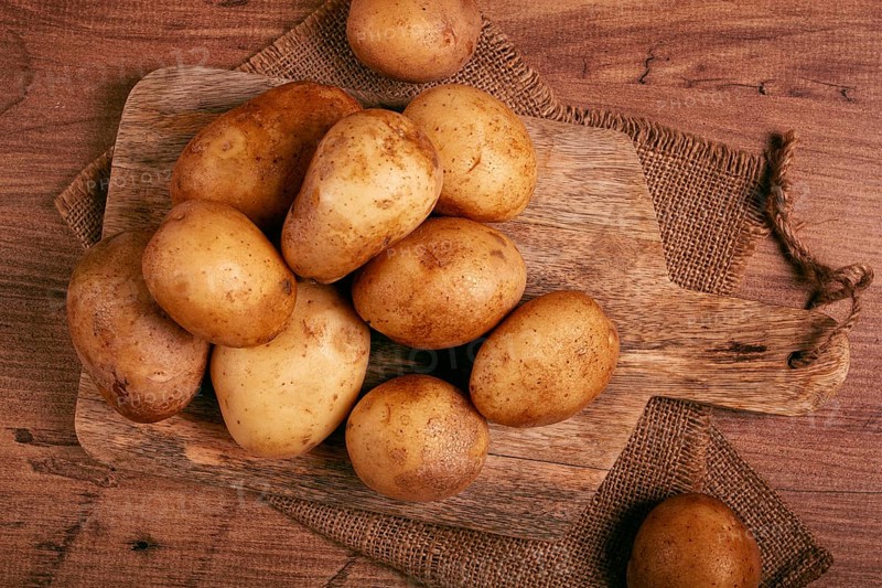 Raw potatoes, scattered on a chopping board, close-up, no people