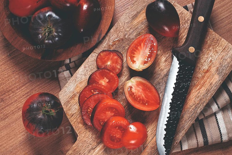Sliced tomatoes, Black Beauty variety, on a cutting board, top view, on the kitchen table