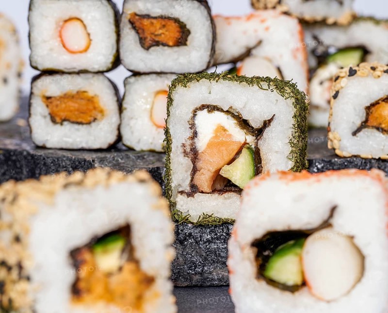 Various sushi dishes on dark grey stone surface