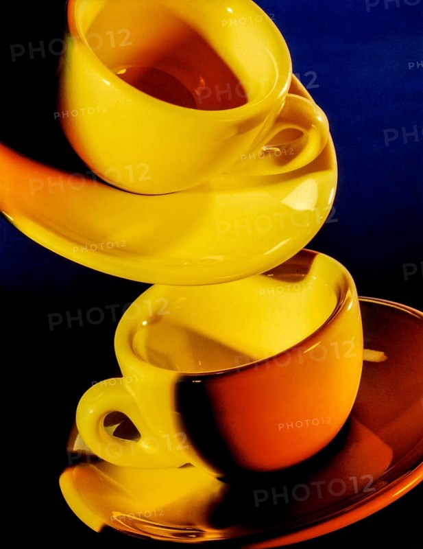 Bright illuminated yellow cups with saucer in dark blue back