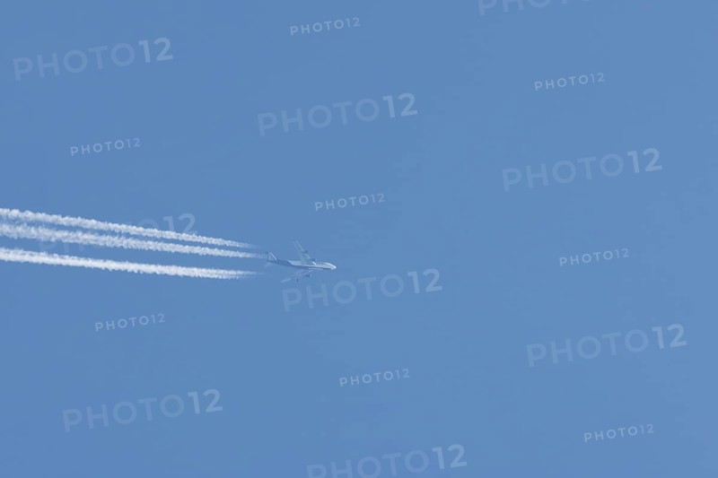 Boeing 747 Jumbo jet passenger aircraft in flight in a blue sky with vapour trails or contrails behind, England, United Kingdom