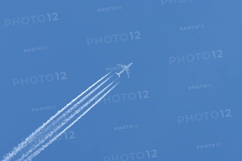 Airbus A340-300 jet aircraft of Lufthansa airlines in flight in a blue sky with vapour trails or contrails behind, England, United Kingdom