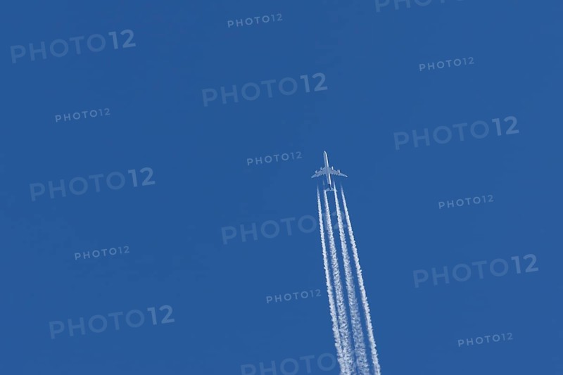 Airbus A340-300 jet aircraft of Lufthansa airlines in flight in a blue sky with vapour trails or contrails behind, England, United Kingdom